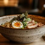 Ramen noodle bowl with soy sauce broth, soft-boiled egg, sliced pork, nori, and green onions