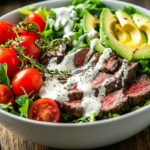 Colorful burger bowl with greens, beef, avocado, and ranch dressing