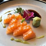 A plate of salmon sashimi with soy sauce and wasabi